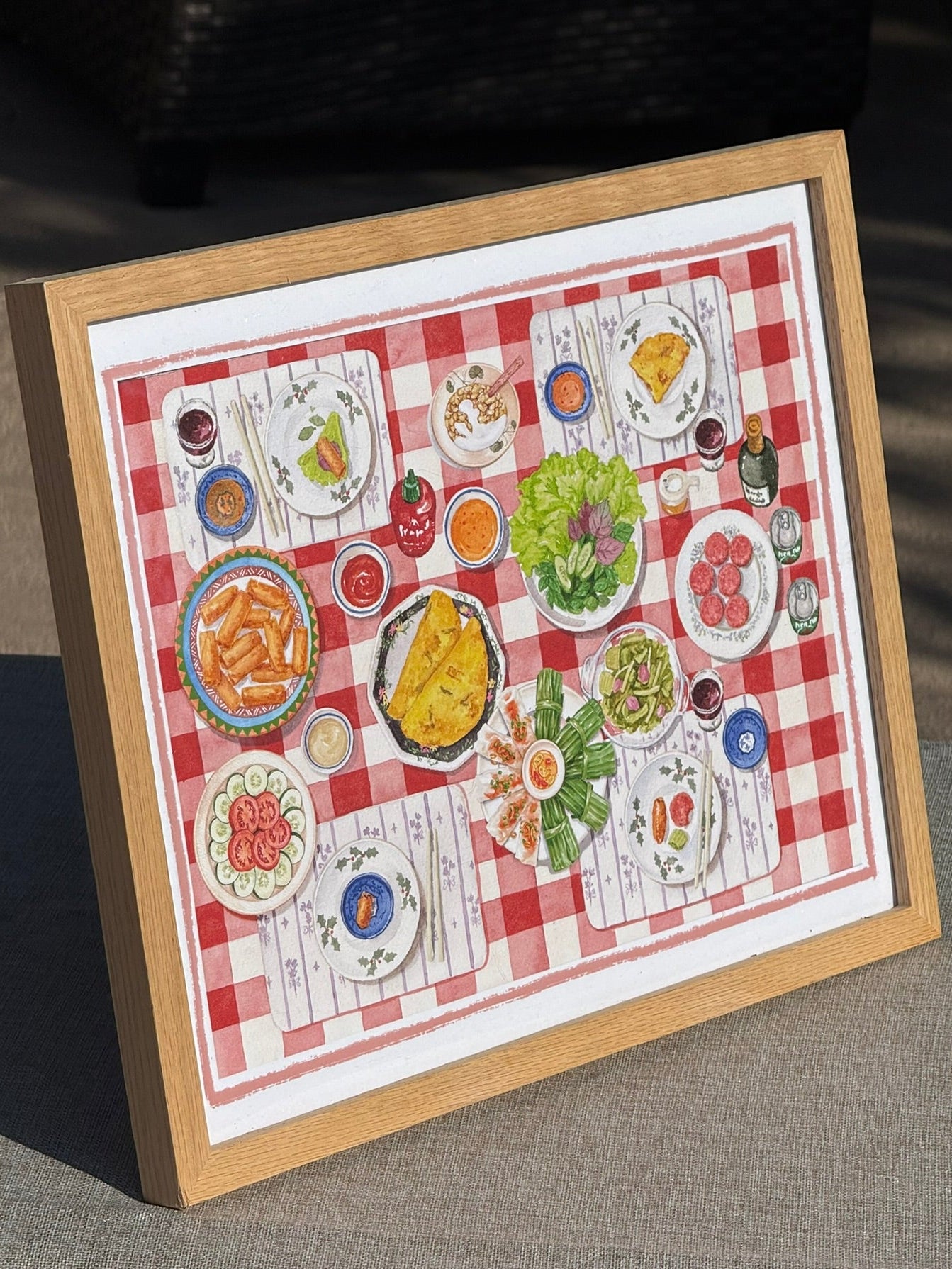 A framed print featuring a colorful table set featuring various Vietnamese ultural dishes.